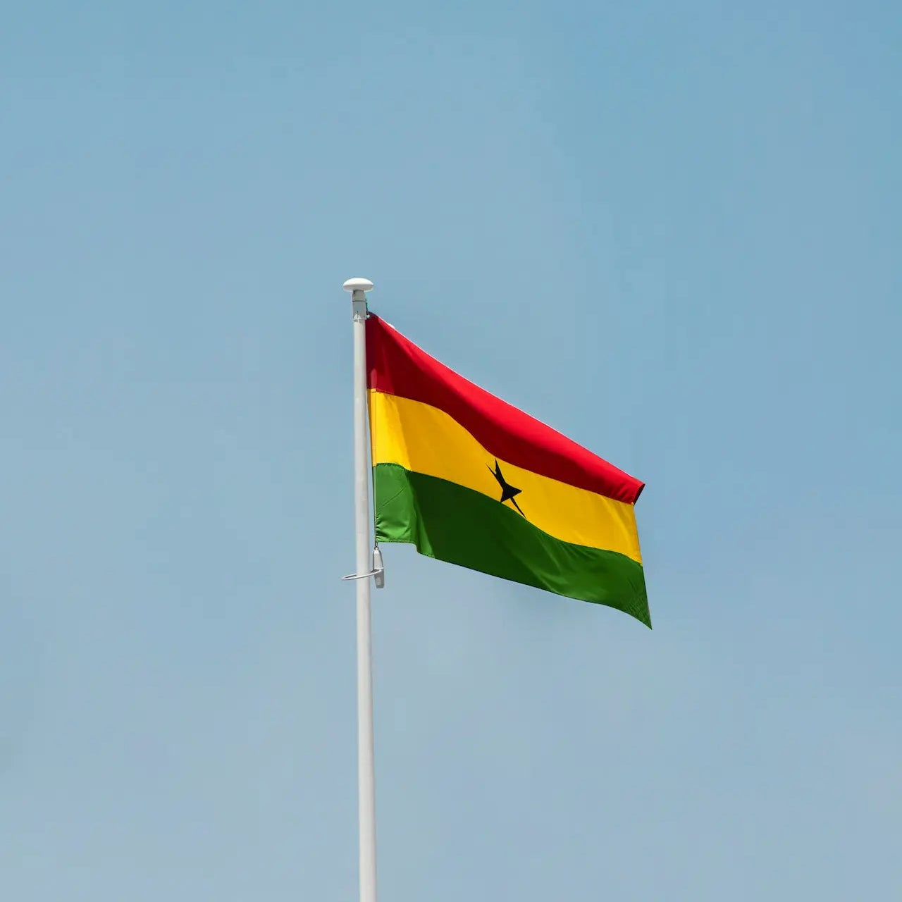 Ghanaian flag waving against a clear blue sky
